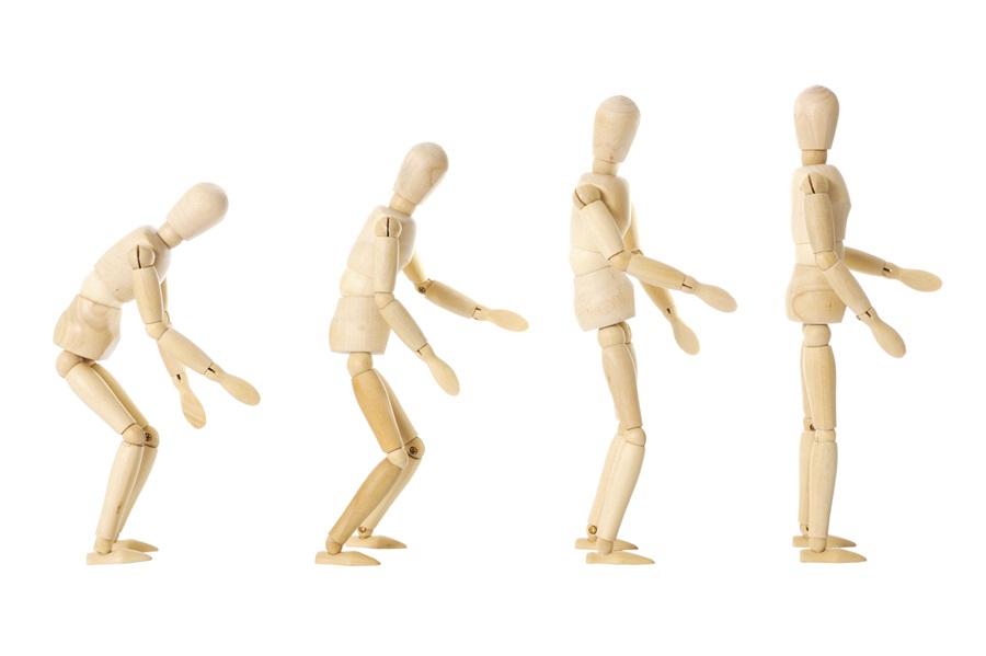 four wooden figures in a row progressively standing up straight 