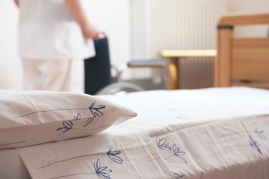 close-up of hospital bed with wheelchair in background